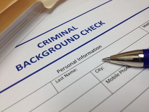 A pen sits on a criminal background check form