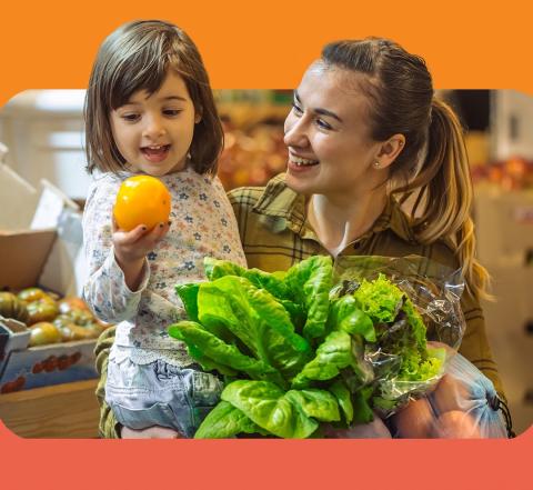 Young girl and mother check out fruit and vegetables in a supermarket